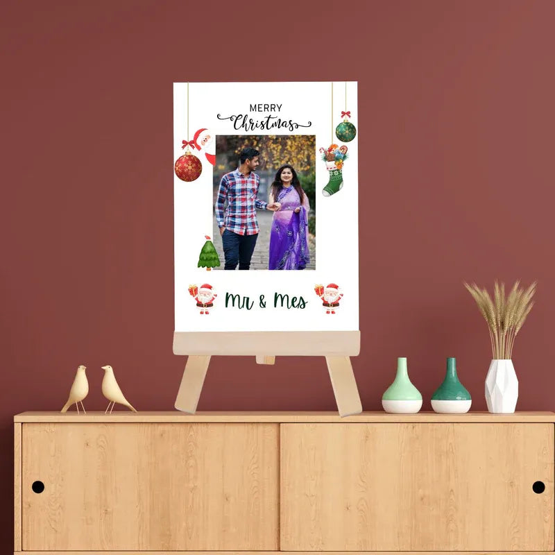 Christmas-themed photo frame with a couple's photo on a wooden cabinet against a red wall.