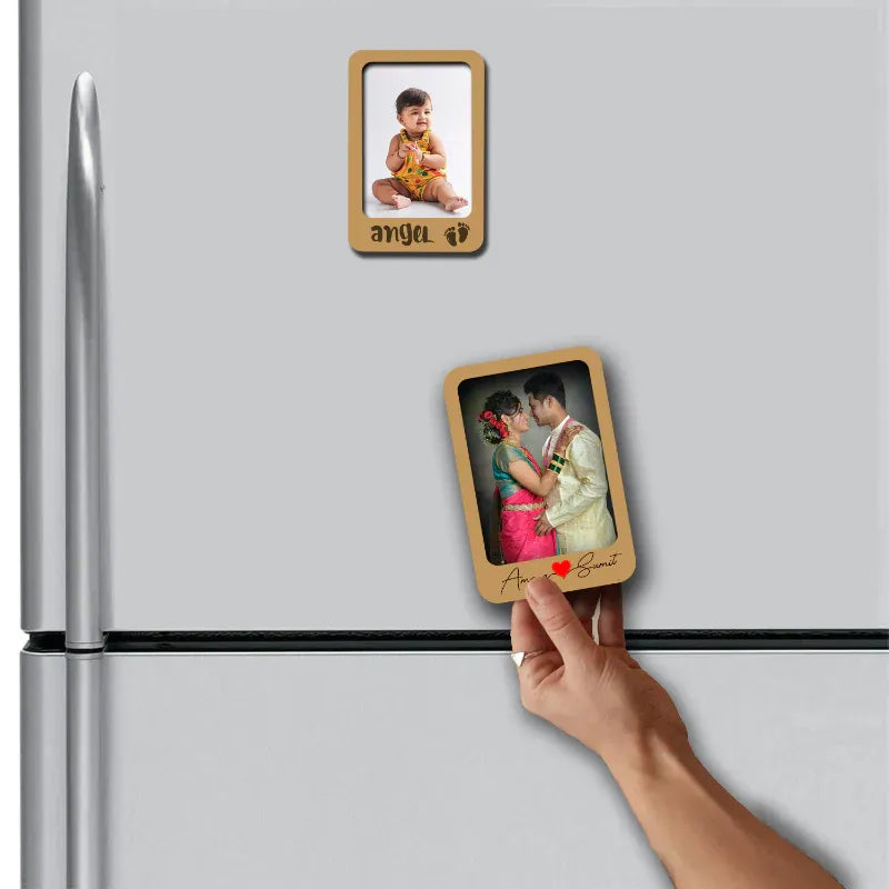Hand placing a wooden photo fridge magnet on a refrigerator with another magnet already attached.