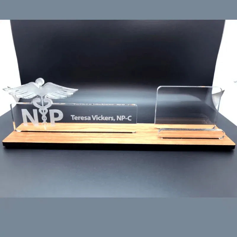 A glass award with a wooden base featuring the Caduceus symbol and engraved text on a dark background.