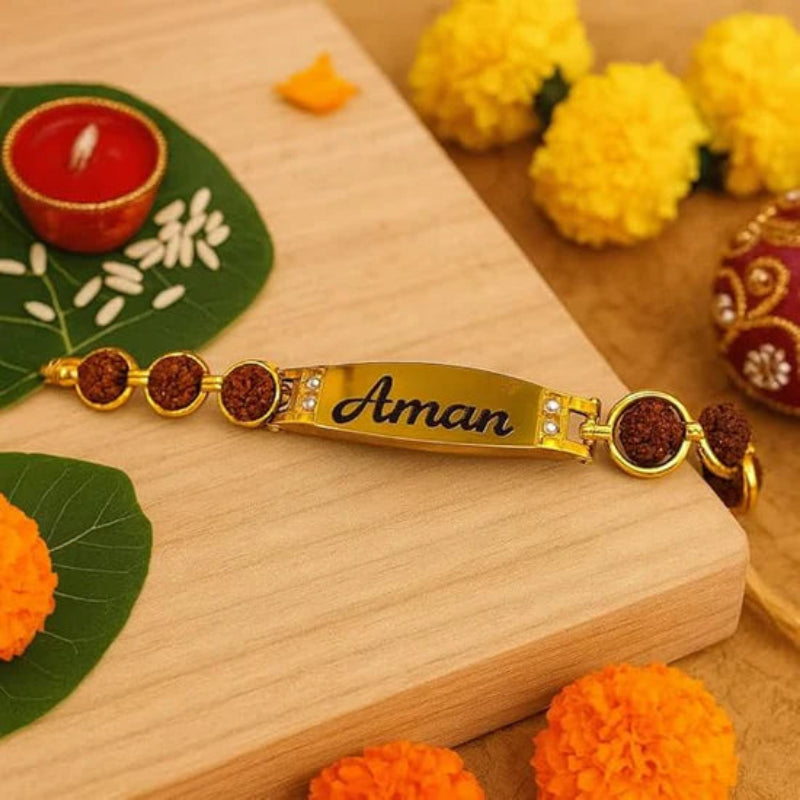 Gold bracelet with 'Aman' engraving on a wooden surface with decorative elements.