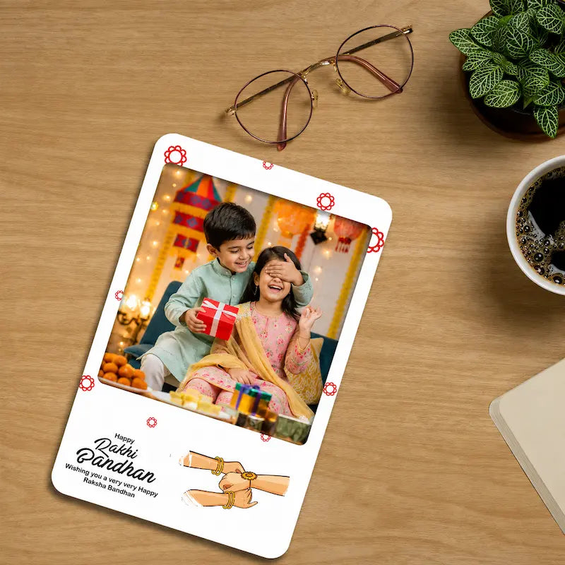 A custom photo birthday card for a brother named 'Dabbie' on a wooden desk, styled with glasses, a potted plant, and a cup of coffee nearby.