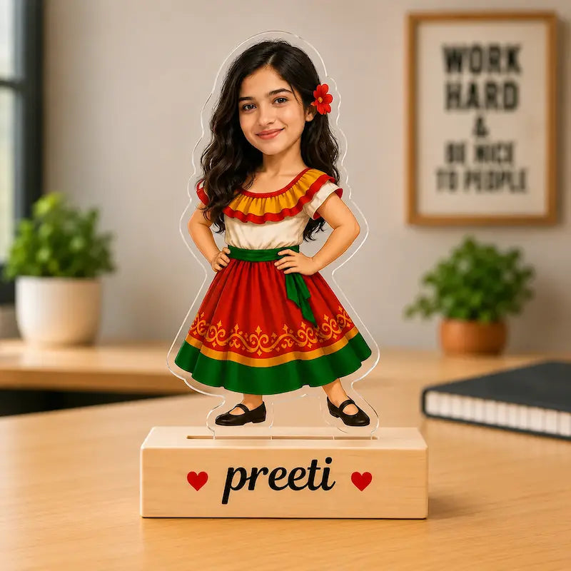 A custom acrylic caricature for daughter of a young girl with long dark hair, wearing a traditional red, green, and white dress, standing on a custom wooden base printed with the name 'Preeti' and small red hearts.