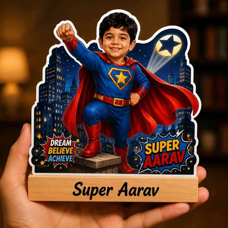 Child in superhero costume with 'Super Aarav' on a wooden stand