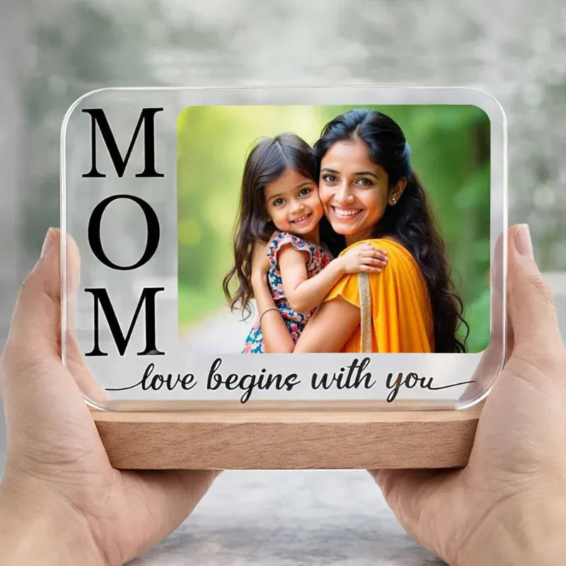 Clear customized photo block with a mother and daughter photo frame and 'MOM love begins with you' text, held by hands.