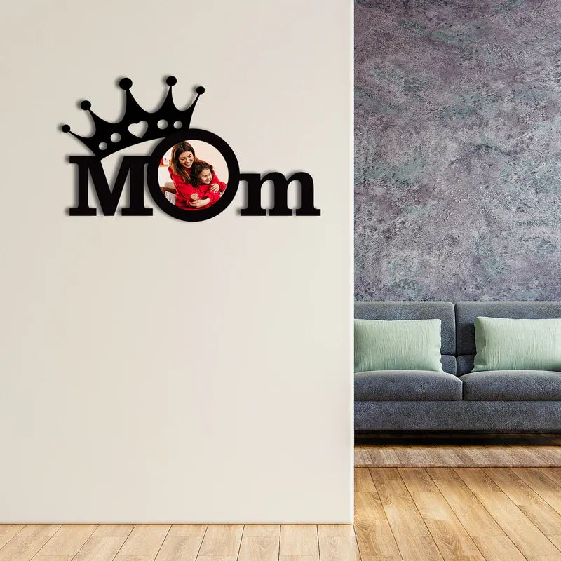 Decorative wall art with 'Mom' and a photo of a family on a white wall next to a gray sofa.