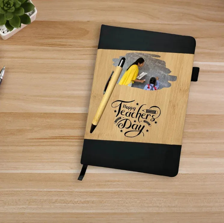 Notebook with 'Happy Teachers Day' text and a pen on a wooden surface