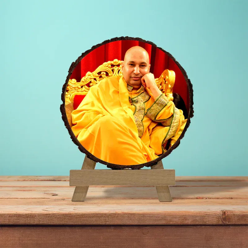 Man in yellow robe sitting on a throne-like chair with a red background, on a wooden stand against a blue wall.
