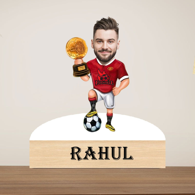 decorative caricature with a person in a red jersey holding a trophy, standing on a soccer ball, with 'RAHUL' displayed below.