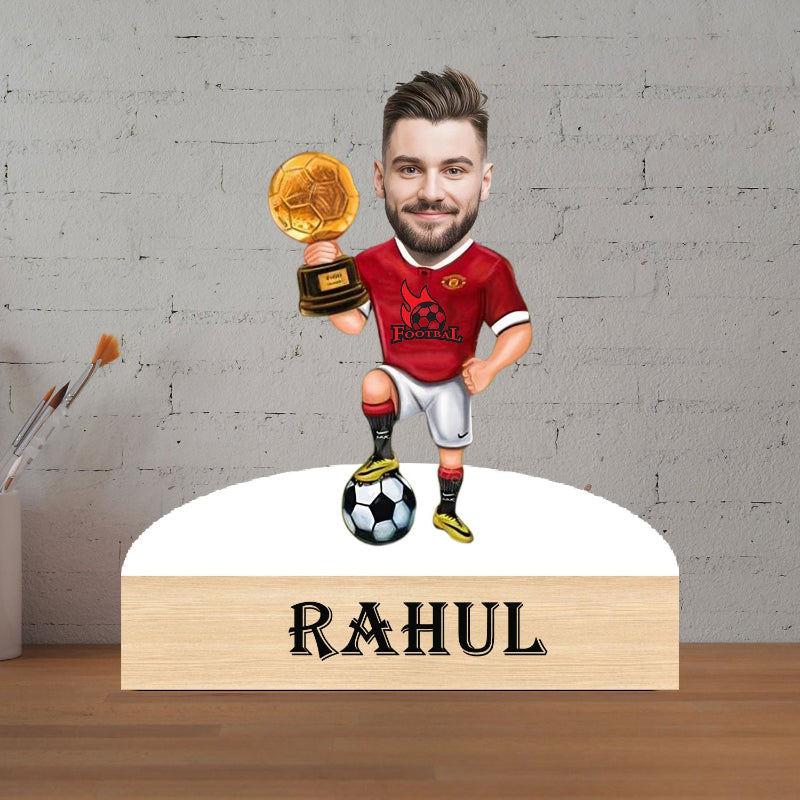 caricature of football player holding a trophy with 'RAHUL' on a base against a gray brick wall.