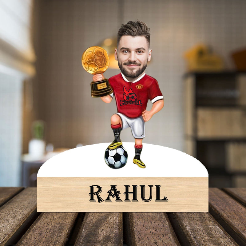 caricature of a man in a red sports jersey holding a trophy, standing on a wooden base with 'RAHUL' engraved.