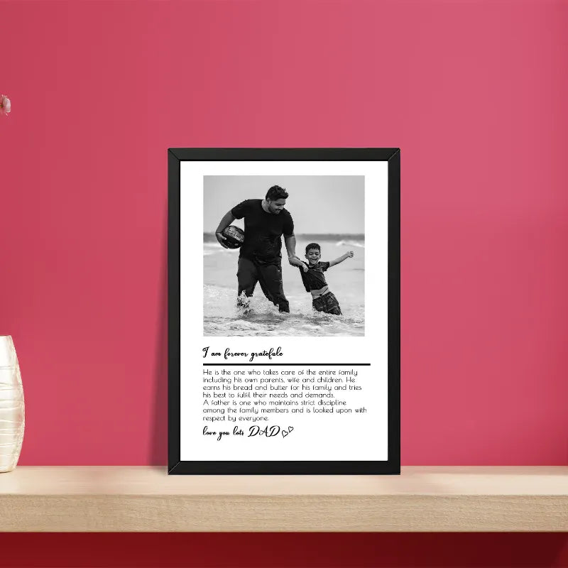 Framed black and white photo of a man and child in water with text on a red wall.