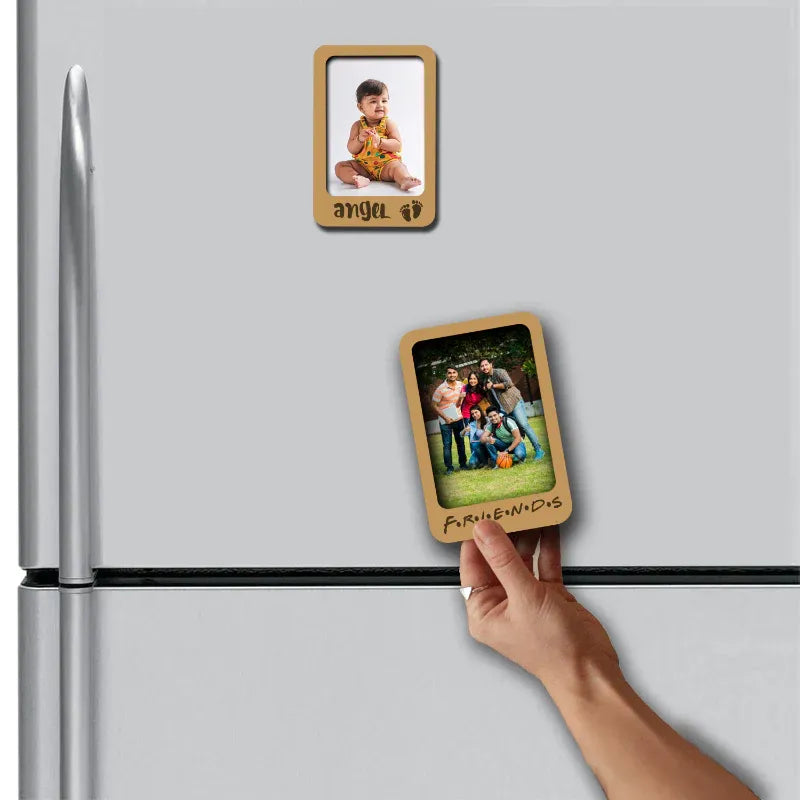 Hand placing a wooden photo frame magnet on a refrigerator with another magnet showing a family photo.