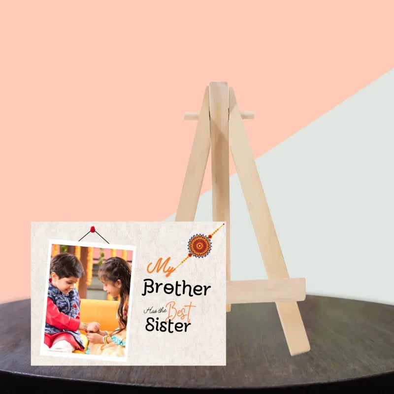 A personalized wooden A-frame easel stand displaying a custom photo print that reads 'My Brother Is the Best Sister' against a pastel pink and light gray background.