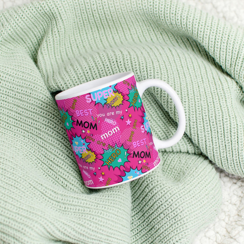 Pink mug with colorful text and graphics on a green textured fabric background