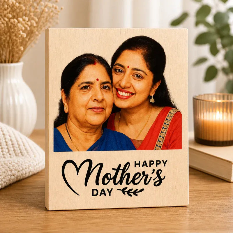 Wooden plaque with a photo of two women and 'Happy Mother's Day' text, placed on a surface with decorative items.