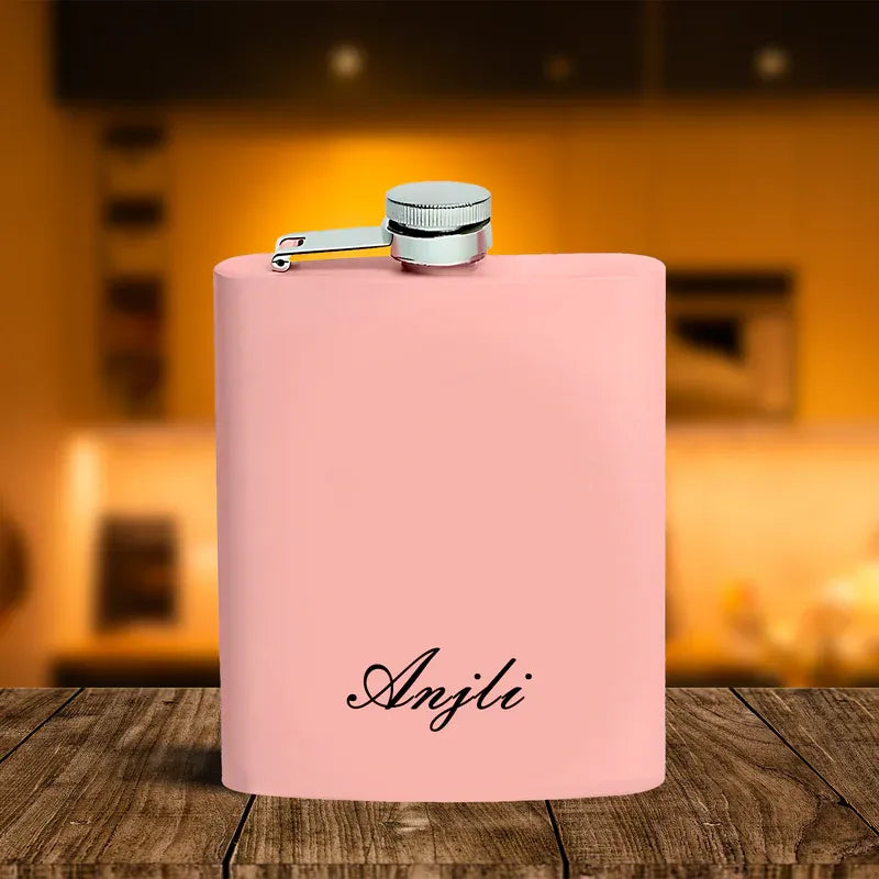 Pink flask with 'Anjli' branding on a wooden surface with a blurred background