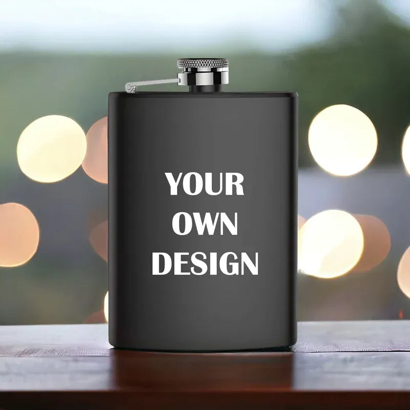 Black flask with 'YOUR OWN DESIGN' text on a blurred bokeh background