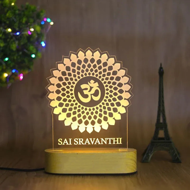 Decorative LED lamp with 'Om' symbol and text, illuminated on a wooden surface.