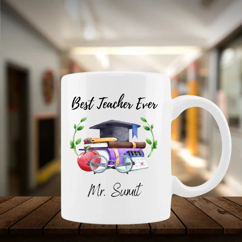 White mug with 'Best Teacher Ever' text and teacher-themed graphics on a wooden surface.