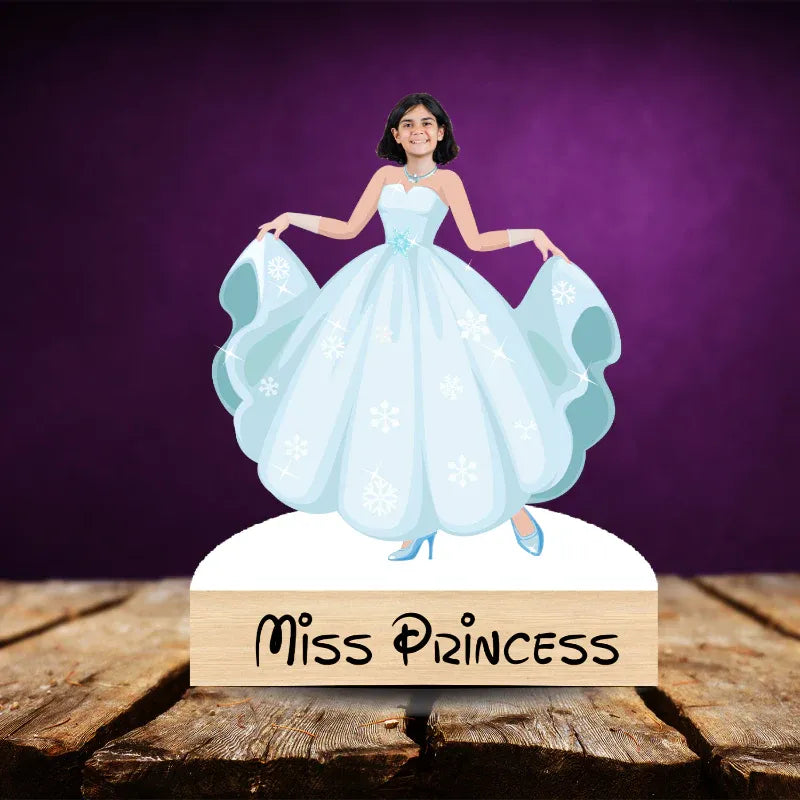 Figurine of a woman in a blue dress with 'Miss Princess' sign on a wooden base against a purple background