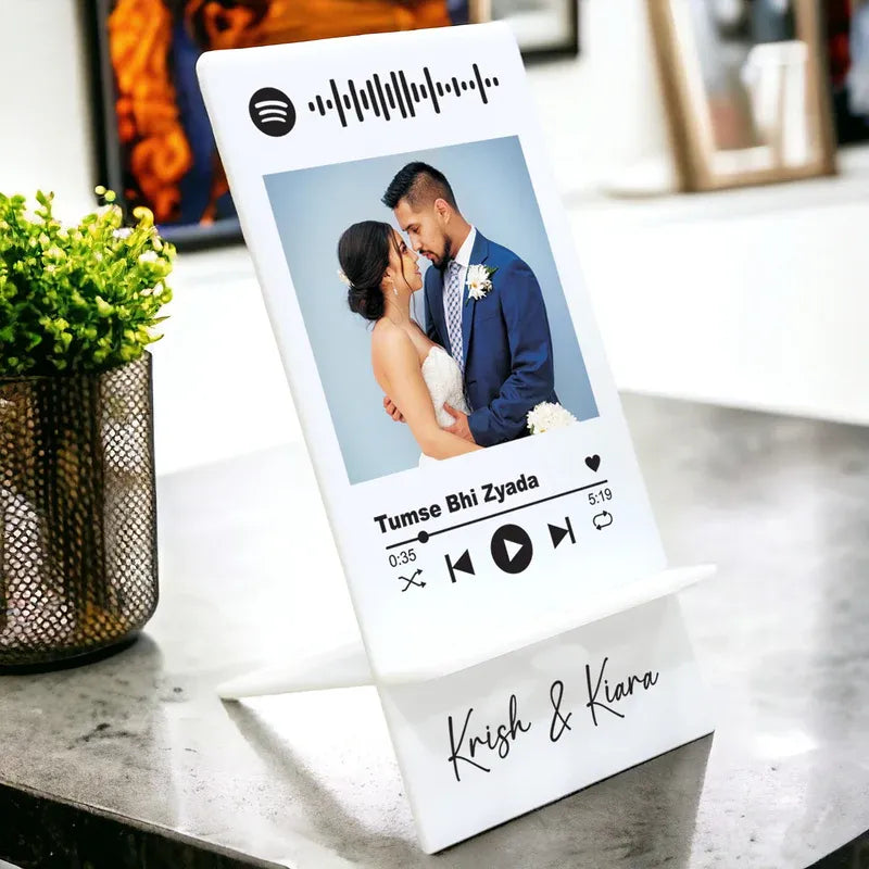 Personalized Spotify photo frame with a couple's photo and music controls on a table.