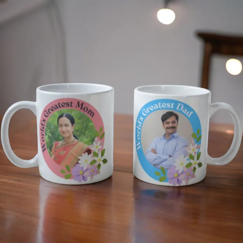 Two mugs with personalized images of a woman and a man, labeled 'World's Greatest Mom' and 'World's Greatest Dad', on a wooden surface.