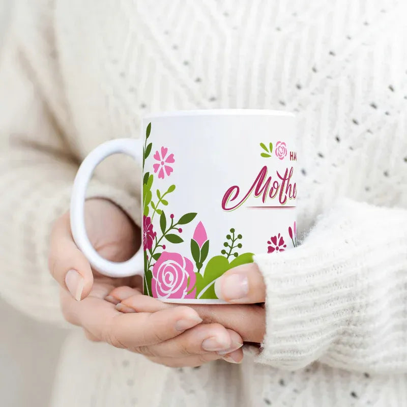 Person holding a mug with floral design and 'Happy Mother's Day' text.