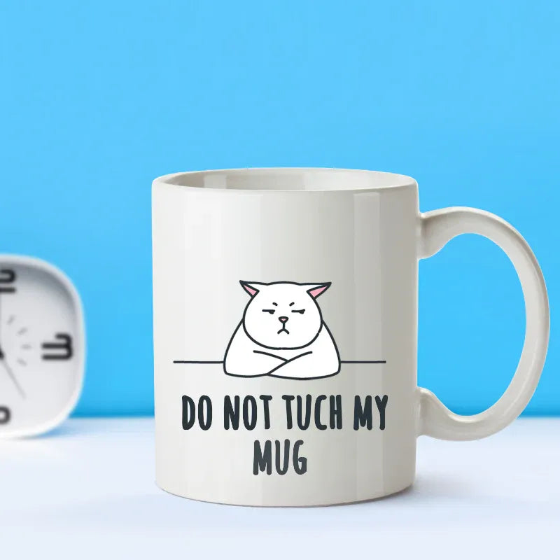 White mug with a cat illustration and text 'Do Not Touch My Mug' on a blue background