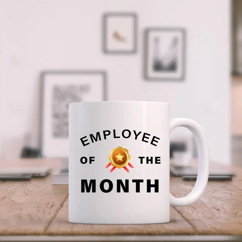 White mug with 'Employee of the Month' text on a desk in an office setting