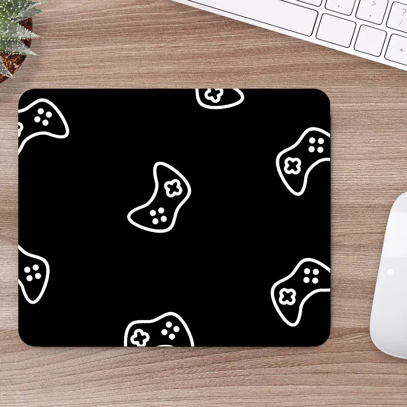 Black mouse pad with white game controller patterns on a wooden desk.