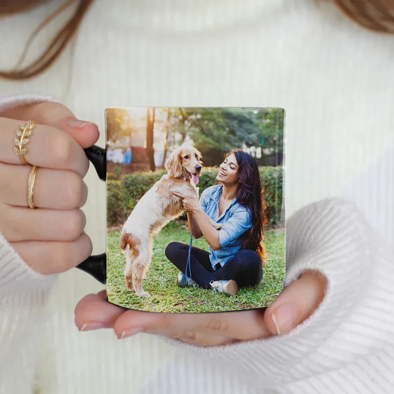 Person holding a mug with a photo of a woman and dog on it