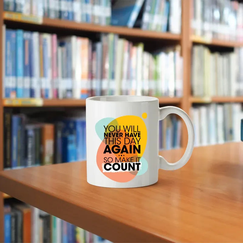White mug with motivational quote on a wooden table in front of bookshelves