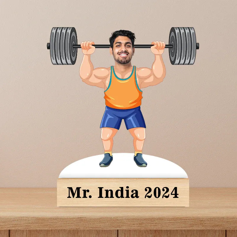 Statue of a man lifting weights with 'Mr. India 2024' text on a wooden base