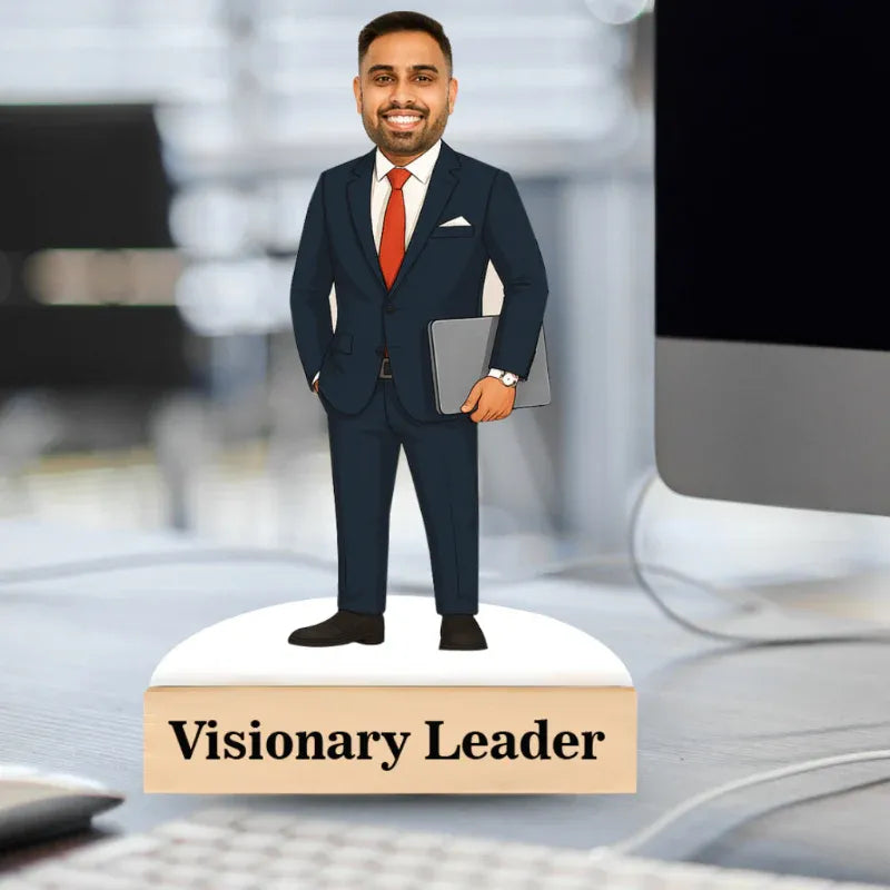 Figurine of a man in a suit labeled 'Visionary Leader' on a desk.