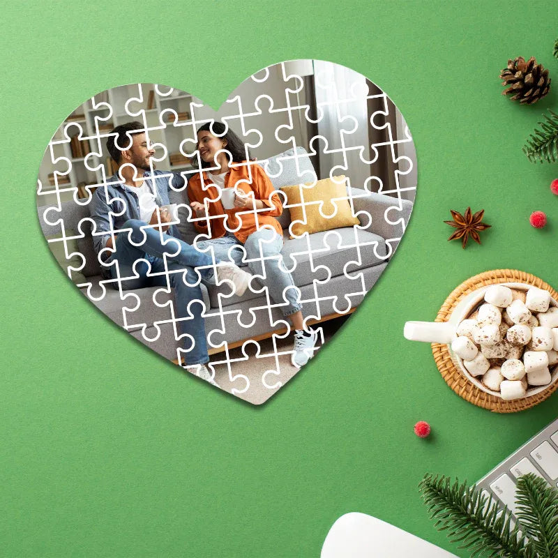 Heart-shaped puzzle with a photo of two people on a green background with decorative items.