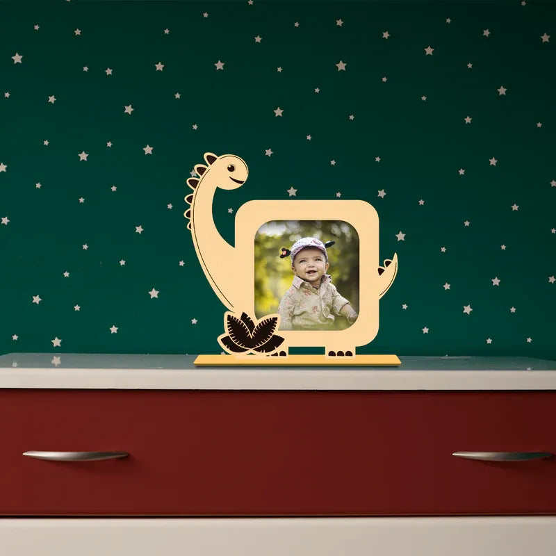 Wooden dinosaur photo frame with a child's picture on a green wall with star patterns.