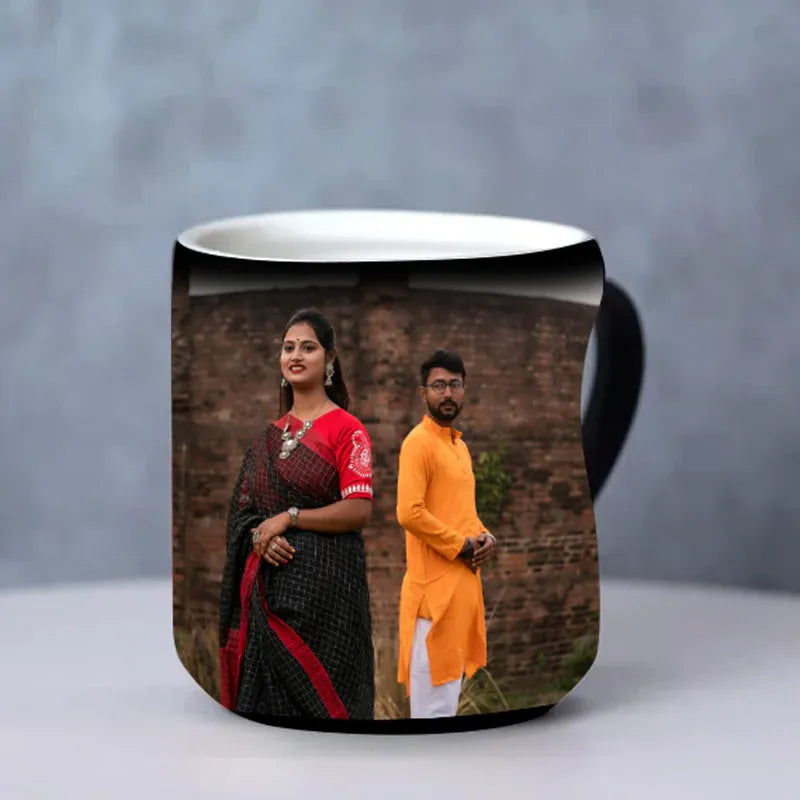 Black mug with a printed design of a couple against a brick wall on a gray background
