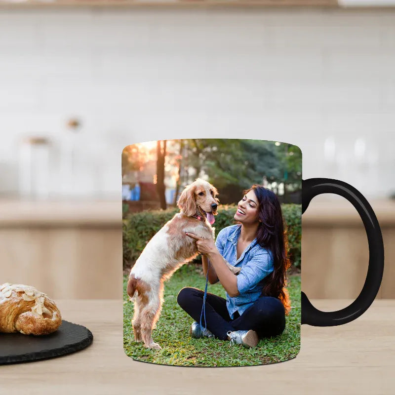 Mug with a photo of a woman and dog on a grassy area, placed on a wooden surface.