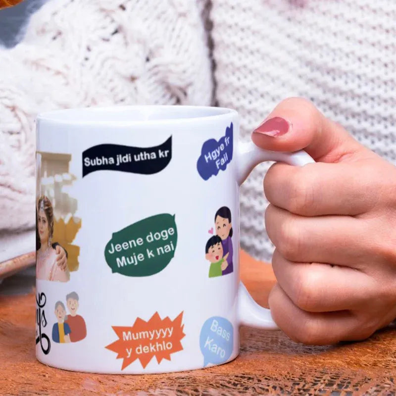 Person holding a mug with various designs and text on a wooden surface.