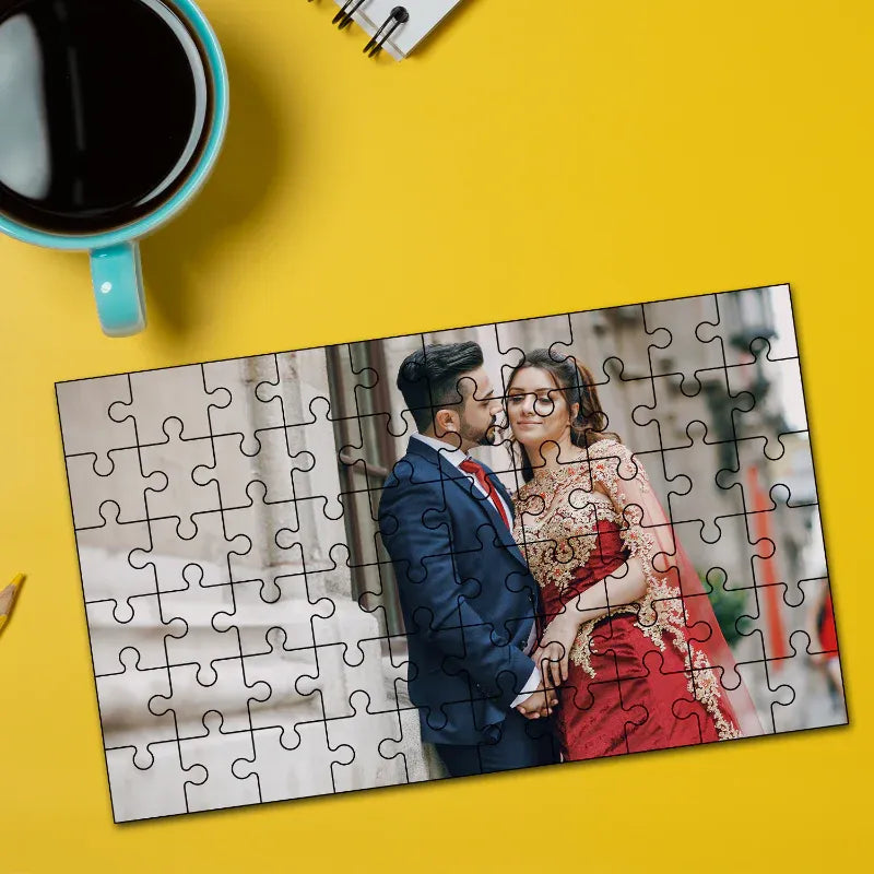 Jigsaw puzzle with a couple on a yellow background next to a cup of coffee.