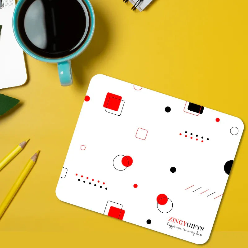 custom mouse pad with geometric pattern on a yellow surface with a cup of coffee and pencils.
