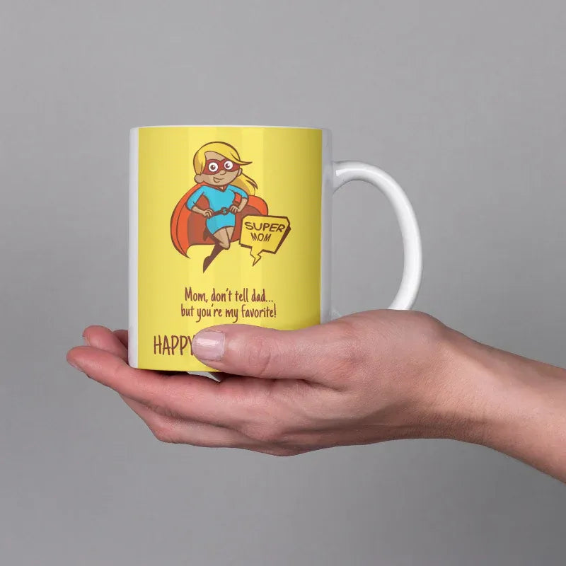 Hand holding a mug with a superhero-themed design on a gray background