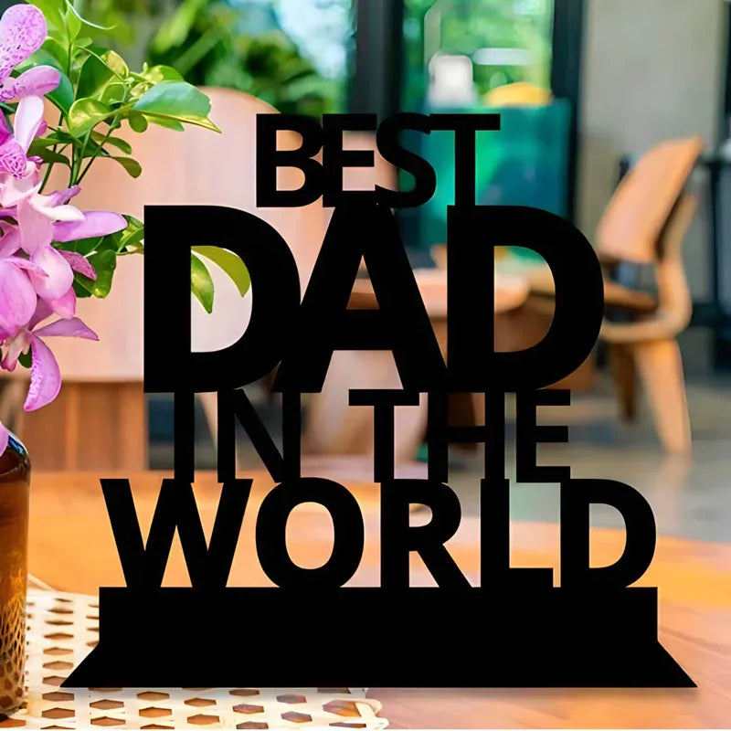 A wooden table top with the inscription 'BEST DAD IN THE WORLD' in black letters, placed on a white surface.