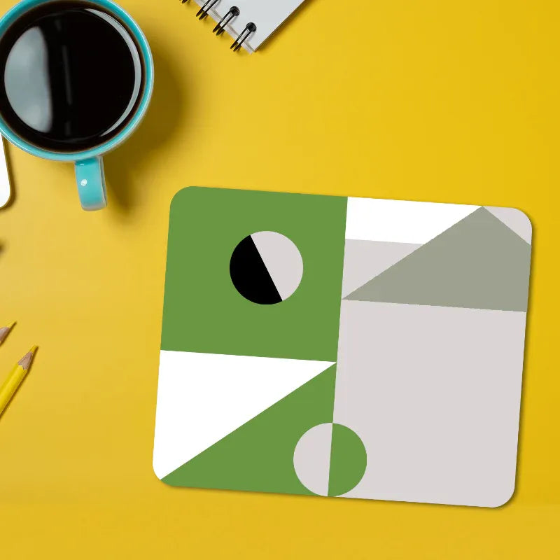 Geometric mouse pad on a yellow surface with a cup of coffee and pencils.