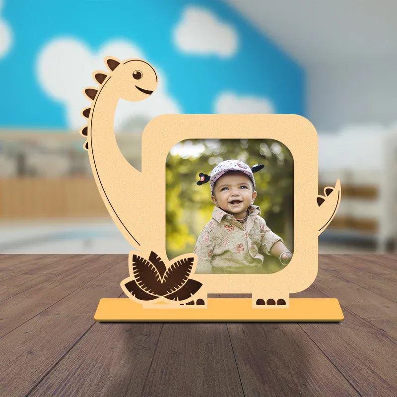 Dinosaur-shaped photo frame with a child's picture on a wooden surface