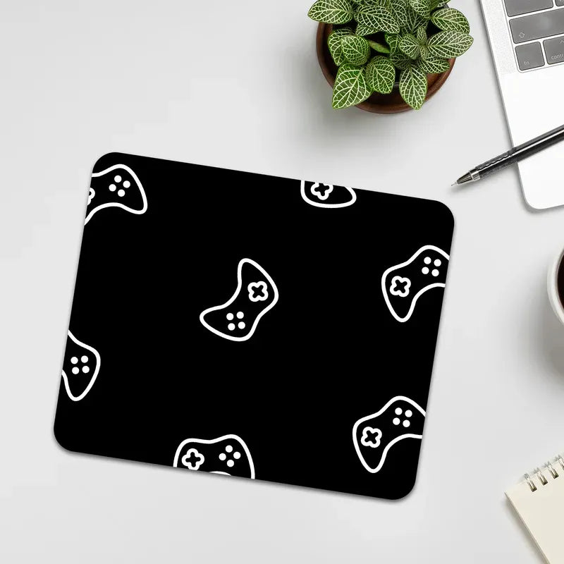 Black mouse pad with white game controller pattern on a light gray surface.