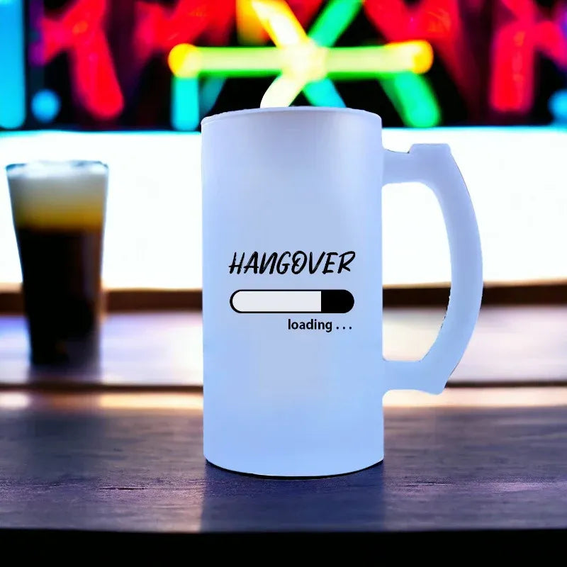 White mug with 'HANGOVER loading...' text on a bar counter with a drink and colorful lights in the background.