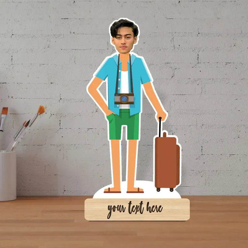 Cardboard standee of a person with a suitcase on a wooden surface with a gray brick wall background.