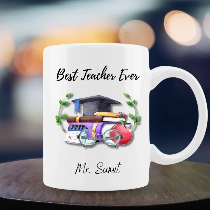 White mug with 'Best Teacher Ever' text and graduation-themed design on a blurred background