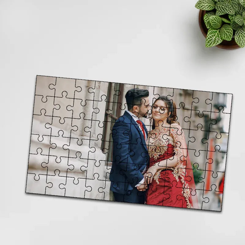 Jigsaw puzzle with a couple in formal attire on a white surface with a plant in the corner.